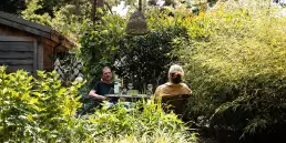 De uitbaters van het hotel genieten in een zithoek in de hotel tuin in lanklaar